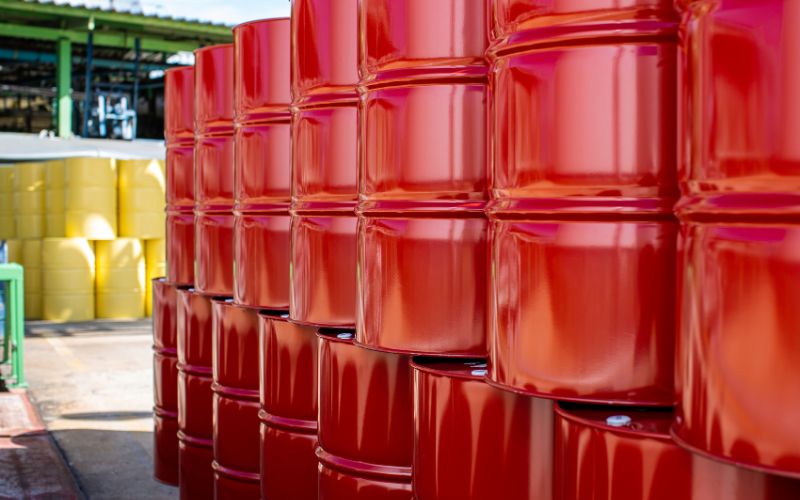 Image of a row of two layers of stacked red barrels or Drums of chemicals and solvents